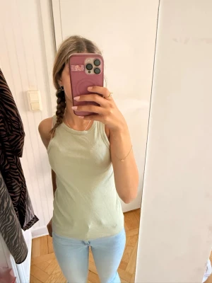 Ljusgrön ribbad linnetopp - Säljer en enkel och fräsch ljusgrön linnetopp i ribbad bomull. Toppen är ärmlös med rund halsringning och har en slim passform som sitter snyggt på kroppen.🌸