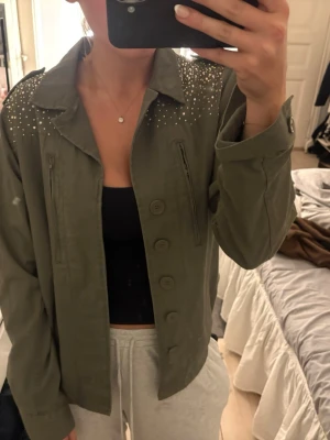 Jeans jacka med paljetter - Höstigare jeans jacka /tyg jacka från vila med paljetter / diamanter på ryggen som går fram . Jätte fin och knappt använd. Köpt på plick sen långt tillbaka, storlek M men passar också S beror lite på hur man vill att den ska sitta. Grön / mörkgrön / khaki
