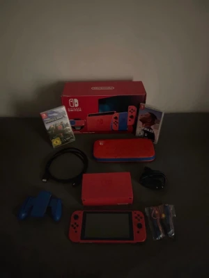 Nintendo Switch röd/blå med spel - Nintendo Switch-konsol i rött och blått med originalkartong, två spel (Minecraft och FIFA 22), laddkabel, dockningsstation, handkontrollshållare och fodral. Perfekt för gaming hemma eller på språng. Allt du behöver för att komma igång direkt!
