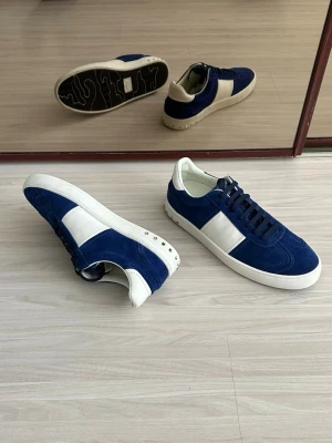 Blåvita sneakers i mocka - Snygga sneakers i blå mocka med vita detaljer och vit sula. Skorna har en klassisk låg siluett och svarta skosnören. Perfekta för dig som vill ha en stilren och trendig look med en sportig touch.
