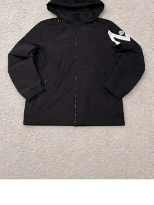 Svart vindjacka med huva Moncler - Svart vindjacka från Moncler med huva och dragkedja framtill. Den passar både M och L perfekt!