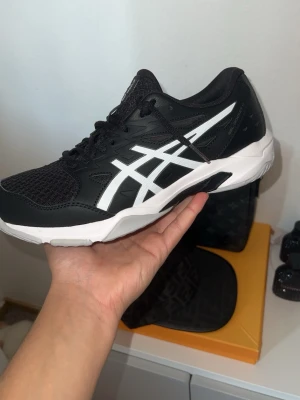 Asics - Snygga svarta Asics sneakers med vit sula och vita detaljer på sidorna. Ovandelen är i mesh och syntetmaterial för bra andningsförmåga och komfort. Klassisk snörning och sportig look som passar perfekt till streetwear. Aldrig använda