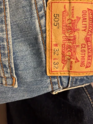 Levi's 505 ljusblå raka jeans - Ljusblå Levi's 505 jeans med raka ben och klassisk femficksmodell. Jeansen har slitna detaljer och en vintagekänsla, tillverkade i bomull med tydliga kontrastsömmar och ikonisk läderpatch bak i midjan.