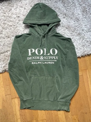 Grön hoodie från Polo Ralph Lauren - Snygg grön hoodie från Polo Ralph Lauren med stor vit logga framtill. Klassisk känguruficka och justerbar huva med dragsko. Mjuk bomullskänsla och avslappnad passform, perfekt för en chill vardagslook. Står XS passar S