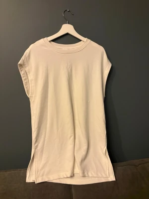 Vit oversized t-shirt från H&M - Säljer en vit oversized t-shirt från H&M Basics. T-shirten har breda ärmhål, rund halsringning och är längre i modellen. Tillverkad i mjukt bomullsmaterial. 