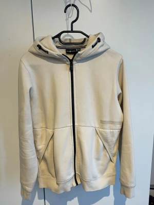 Sailracing hoddie - Snygg hoodie med dragkedja och två stora fickor framtill. Huva med snörning och ett diskret svart märke på huvan baktill. Tillverkad i mjukt sweatshirtmaterial, perfekt för en avslappnad stil.