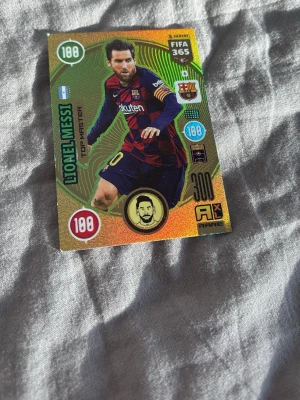 FIFA 365 samlarkort Lionel Messi - Säljer ett glittrigt samlarkort från FIFA 365 med Lionel Messi i Barcelona-tröja. Kortet har färger i guld, grönt och rött samt flera detaljer och stats. Perfekt för dig som gillar fotboll och samlar på kort.