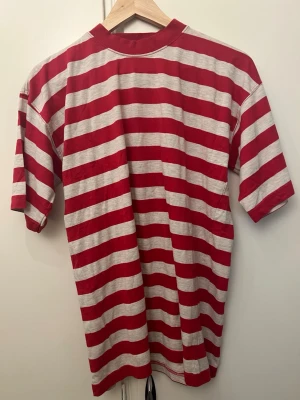 Röd och vit randig t-shirt - Säljer en röd och vit randig t-shirt med breda horisontella ränder. T-shirten har korta ärmar och är gjord i mjuk bomull. Perfekt för en avslappnad och stilren look.