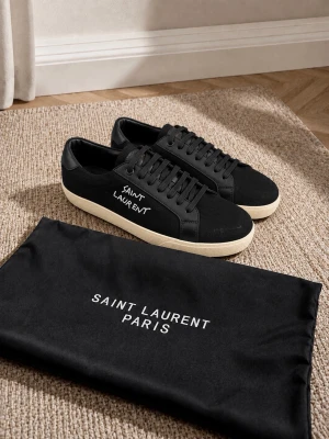 Svarta Saint Laurent Canvas Low  - Snygga svarta sneakers från Saint Laurent med vit logga på sidan och klassisk vit sula. Skorna har en låg profil, svarta skosnören och är tillverkade i en mix av canvas och läder. Perfekta för dig som gillar stilrena och exklusiva sneakers. Feta skor från Saint Lauren i storlek 44.