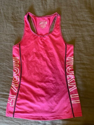Rosa träningslinne från Skill Sport 158/164 - Snyggt rosa träningslinne från Skill Sport med texten 'WORK IT' längs sidorna. Tillverkat i 91% polyester och 9% spandex för en stretchig och bekväm passform. Stl.158/164