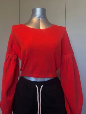 Färgstark stickad crop top från Zara Knit i storlek S ❤️ - Modell med båtringning och extra långa, vida ballongärmar. Mjukt och stretchigt material med 65% viskos. Snygg till högmidjade jeans eller kjol.  Mått finns på bilderna. Samfraktar gärna vid köp av flera plagg.  Material: 65% viskos, 33% polyamid, 2% elastan Storlek: S Färg: Röd/orangeröd