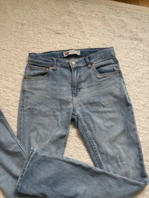 Levi's 512 Slim ljusblå jeans - Säljer ett par klassiska Levi's 512 Slim jeans i ljusblå tvätt. Jeansen har fem fickor, smal passform och snygga detaljer med kopparfärgade nitar. Perfekta för dig som gillar en avslappnad men stilren look. Materialet är denim i bomull.