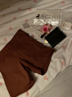 Bruna cykelshorts i stretchigt material - Snygga bruna cykelshorts i stretchigt material med hög midja. Perfekta för en avslappnad look eller till träning. Shortsen har en tight passform och är tillverkade i ett mjukt syntetmaterial som sitter skönt mot kroppen.
