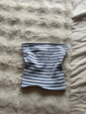 Blåvit randig tubtopp Gina Tricot - Säljer en blåvit randig tubtopp från Gina Tricot i storlek XS. Toppen är axelbandslös och har ett klassiskt bandeau-snitt. Perfekt till sommaren och enkel att matcha med jeans eller kjol. Säljer även på vinted @caisaborelius
