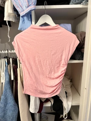 Ljusrosa ärmlös topp - Säljer en ljusrosa topp med ärmlös design och går upp lite i halsen jättefin
