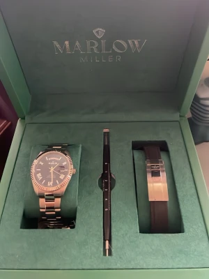 Marlow Miller klockset med blå urtavla - En knappt använd o näst intil fläckfri klocka från Marlow Miller med en stilren silverfärgad metall och blå urtavla. Setet innehåller även ett extra svart armband och ett verktyg för att byta band. Klockan har romerska siffror och datumvisning. Perfekt för dig som gillar klassisk men modern stil. Med knvitto o grattis bytning av band i upp till 2år
