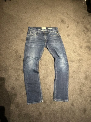 Blå jeans från Replay Rocco - Snygga blå jeans från Replay, modell Rocco. Jeansen har en klassisk femficksdesign, normal midja och raka ben. Tillverkade i slitstarkt denim med snygga slitningar och tvättade detaljer. Perfekta för en avslappnad och trendig look. Size 30/32 