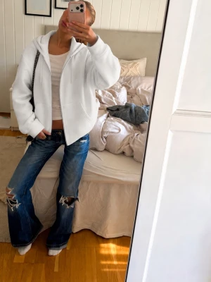 Vit zip hoodie med huva - Säljer en clean vit hoodie med dragkedja och huva. Hoodien har fickor framtill och ribbade muddar vid ärmar och nederkant. Perfekt oversized fit för en chill och avslappnad stil. Materialet är mjukt och skönt inuti.