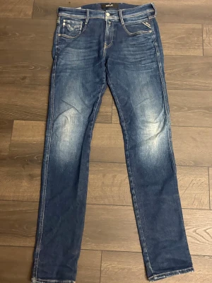 Blå replay anbass jeans  - Säljer ett par blå slim fit jeans med snygga slitningar och ljusa partier på låren. Jeansen är gjorda i ett skönt material som är stretchigt.   W30 L34 