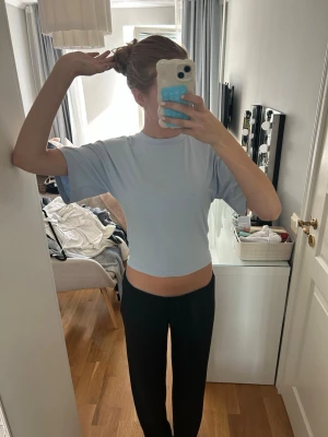 Ljusblå croppad t-shirt - Säljer en ljusblå croppad t-shirt med rund hals och korta ärmar. T-shirten har en enkel och clean look, perfekt till jeans eller kjol. Materialet känns mjukt och stretchigt, troligtvis bomull eller en bomullsblandning.