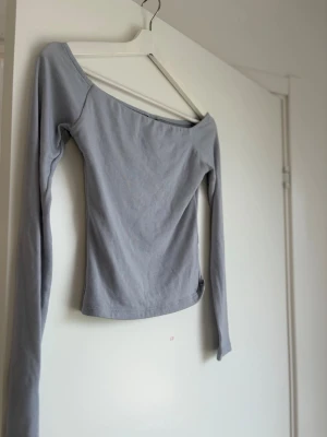 Ljusgrå offshoulder topp Gina Tricot - Säljer en ljusblå offshoulder topp från Gina Tricot i storlek XS. Toppen har lång ärm och är tillverkad i mjukt bomullsmaterial. Perfekt för dig som gillar en enkel men snygg stil.