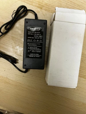 Svart 48V laddare till elscooter  - Säljer en svart 48V laddare med trepolig kontakt, passar till olika elektronikprylar som elcyklar eller elscootrar. Kommer med strömadapter och originalkartong. Tillverkad i plast och har tydlig märkning på ovansidan.