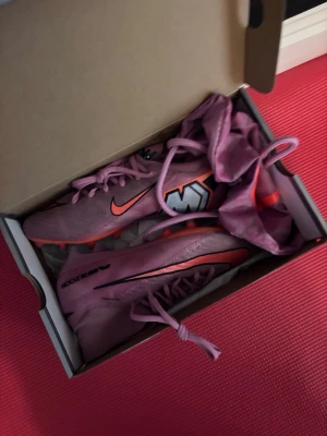  Nike Mercurial elite ag  fotbollsskor i 37,5 - Säljer ett par rosa Nike Mercurial fotbollsskor med påse o originalbox. Använt ca 5ggr. Nypris 3200kr
