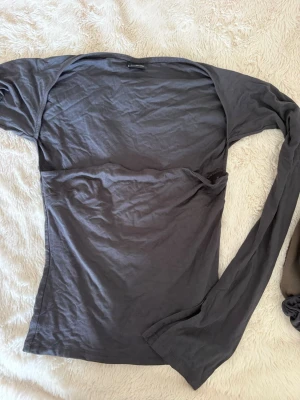 Gina tricot långärmad topp - Snygg och lite annorlunda topp från Gina Tricot med en tubtoppsliknande design framtill, samtidigt som den har långa ärmar och tyg som går över magen. Den sitter figurnära och ger en fin, stilren siluett. Perfekt att matcha med jeans, kjol eller kostymbyxor.  • Storlek S • Använd ett fåtal gånger • Inga defekter • Fint skick ✨