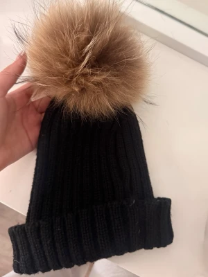Mössa med pälsboll - Säljer min fina hollies mössa med en jätte söt päls boll. - pälsen är äkta päls, mössan är i fint skick o har inga fläckar eller liknande!🩷🩷 priset går att diskutera vid snabb affär