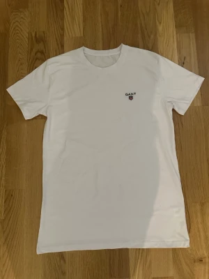 Gant T-shirt - Klassisk vit t-shirt från GANT med liten logga på bröstet. T-shirten har rund halsringning och korta ärmar. Tillverkad i mjuk bomull för en skön känsla och enkel stil som funkar till allt.