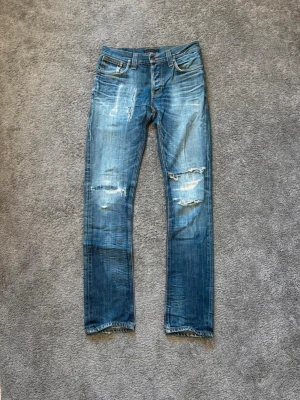 Nudie jeans  - Snygga nudie jeans med slitningar. Det finns ett hål på baksidan under en av fickorna, syns inte särskilt mycket när man har på sig dem. Modell: Grim Tim Mått finns de är bara att skriva till mig så skickar jag dom!