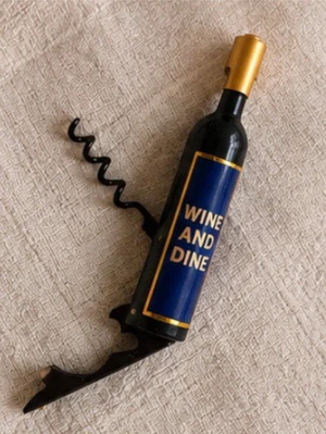 Vinöppnare i flaskform - Snygg vinöppnare/kapsylöppnare formad som en vinflaska med texten 'WINE AND DINE' på blå etikett. Kroken och öppnaren är i svart metall och flaskan har guldfärgad topp. Perfekt till köket eller som present till vinälskare.