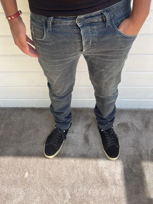 Diesel jeans grå - Hej, säljer dessa snygga grå diesel jeans med tapered passform. Har lite mer utrymme än vanliga slim jeans och är riktigt bekväma. Modellen på bilden är 173cm och väger 74kg. Materialet består av 97% bomull och 3% elastan. Hör gärna av dig vid intresse! Mvh