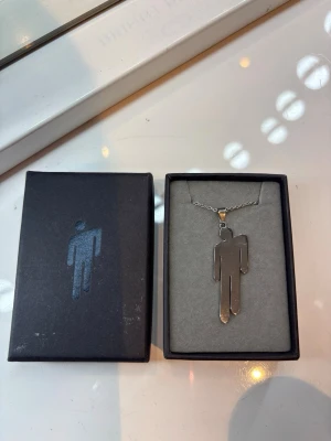Og 2019 Billie Eilish stainless steel blohsh necklace  - Unikt halsband med ett silverfärgat hänge i form av en stiliserad mänsklig figur. Kedjan är tunn och elegant, och hänget har en modern, minimalistisk design. Perfekt för dig som gillar enkla men uttrycksfulla accessoarer. (lådan ingår) köpt från billie’s hemsida under 2019💕säljer pga att den inte kommer till användning längre. halsbandet har några repor. Priset kan sänkas vid snabb affär ⭐️