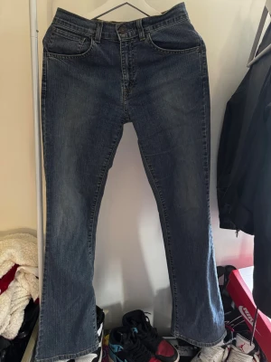 Mörkblåa Levis jeans - Säljer ett par klassiska vintage Levis jeans i midrised. Dom är i en fin mörkblå denim med fem fickor och dragkedja. Jeansen har en lätt tvättad look och raka ben som går ut till en fin bootcut. Passar perfekt för dom med storlek 36 i jeans, dom är lite långa på mig som är 163cm lång.