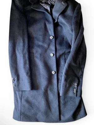 Hugo Boss Kashmirkappa (M) - Hugo Boss herrkappa i svart. Mycket gott skick. Tillverkad av 100% kashmir. Köptes ursprungligen för 10 000 kr. Medium storlek. Storlek 46 DE. Storlek 46 FR. Storlek 46 UK. Storlek 46 IT. Storlek 36R US. Storlek 36R MX.