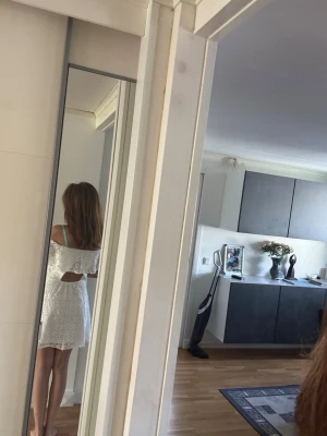 Vit offshoulder spetsklänning - Söt vit kortklänning i spets med offshoulder och volangdetalj. Klänningen har öppen rygg och är ärmlös, perfekt för sommarens alla tillfällen. Materialet är spets och bomull för en luftig känsla.