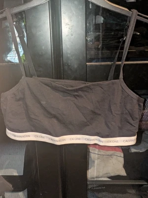 Svart Calvin Klein bralette - Snygg svart bralette från Calvin Klein med smala axelband och elastisk resår med logga i vitt och grått. Tillverkad i mjuk bomullsblandning för extra komfort. Några små fläckar som säkert går.bort i tvätten