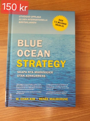 Blue Ocean Strategy bok - En inbunden bok med blått omslag och titeln 'Blue Ocean Strategy'. Boken handlar om att skapa nya marknader utan konkurrens och är skriven av W. Chan Kim och Renée Mauborgne. Omslaget har en vattenyta och text i vitt och gult.