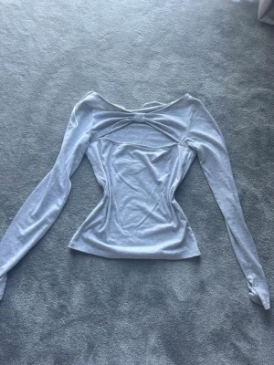 Ljusgrå långärmad topp med snörning - Trendig ljusgrå topp med lång ärm och snygg snörningsdetalj. Perfekt för dig som gillar stilrena och moderna plagg.