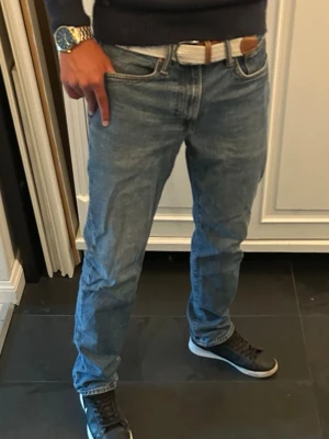 Jeans regular straight fit - Säljer ett par klassiska blå jeans med rak passform och fem fickor. Jeansen har normal midja, bälteshällor och är tillverkade i denim. Perfekta för en avslappnad och stilren look.