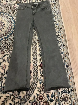Grå bootcut jeans med hög midja 164 13/14 år - Säljer ett par gråa bootcut jeans med hög midja och klassiska fem fickor. Jeansen har utsvängda ben och är tillverkade i ett mjukt denimtyg. Perfekta för dig som gillar en retro och avslappnad stil.