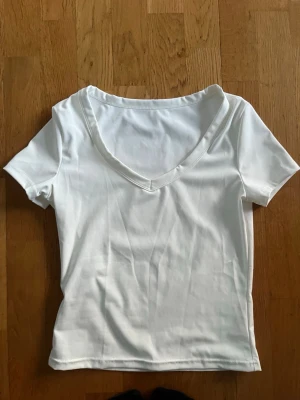 Vit v-ringad t-shirt - En enkel och stilren vit t-shirt med v-ringning och korta ärmar. Perfekt basplagg att matcha med allt.