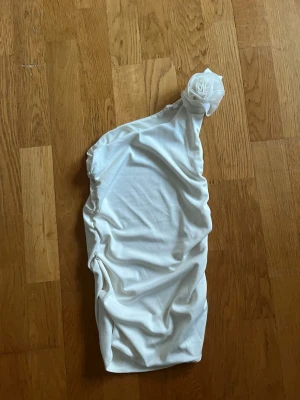 Vit of shoulder linne med blomma på axel - Jag säljer ett vitt linne som är of shoulder med blomma på axeln. Tajt. 