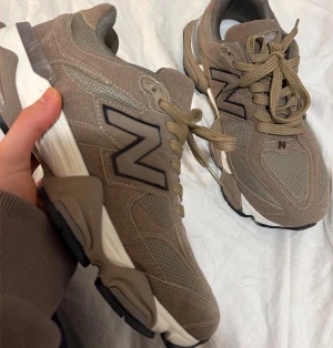 Beige New Balance sneakers - Snygga beige sneakers från New Balance med mesh och mockadetaljer. Skorna har en chunky sula i vitt och beige samt den klassiska N-loggan på sidan. Perfekta för en trendig och sportig look.