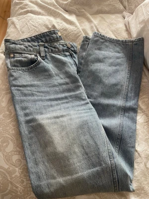 Ljusblå raka jeans - Säljer ett par ljusblå jeans med rak passform och klassisk femficksdesign. Jeansen har hög midja och är tillverkade i denim med en snygg tvättad look. Perfekta för en avslappnad och trendig stil.