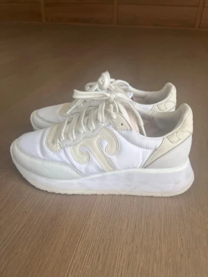 Vita sneakers med beige detaljer - Säljer ett par sjukt snygga vita sneakers med beige detaljer och tjock sula. Skorna har snörning och en unik beige design på sidan. Tillverkade i en mix av textil och syntetmaterial. Perfekta för dig som gillar stilrena och trendiga sneakers.💕Det går bra med förhandlingar💕💕