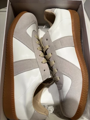 Maison Margiela gats vit/beige - Maison Margiela gats i vitt och beige med klassisk gummisula. Skorna är helt nya i storlek 44 men passar för storlek 43. 