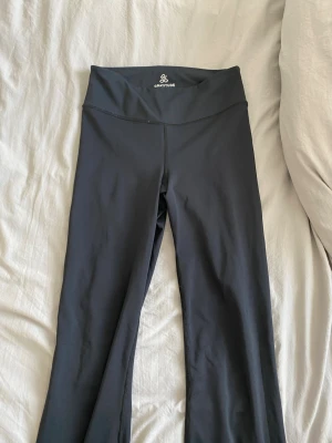 Svarta bootcut leggings Gratitude - Snygga svarta leggings från Gratitude Apparel i storlek XS. Modellen har hög midja och bootcut-ben, vilket ger en trendig siluett. Tillverkade i ett stretchigt och mjukt material som sitter skönt på kroppen. Perfekta för en avslappnad och sportig look.