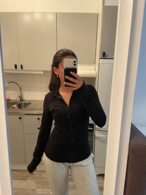 Lululemon define jacket - Säljer en svart ziptröja med figurnära passform och långa ärmar med tumhål. Tröjan har dragkedja framtill och två fickor. Perfekt för en sportig och avslappnad stil.